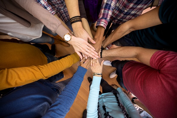 team of employees with hands stacked