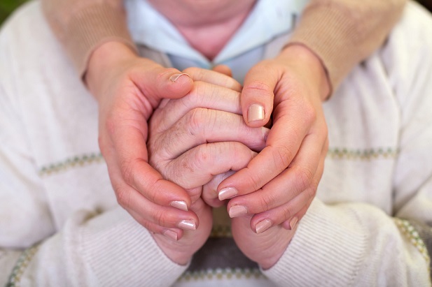 old hands clasped by younger hands