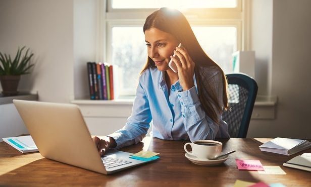 woman at laptop using cellphone