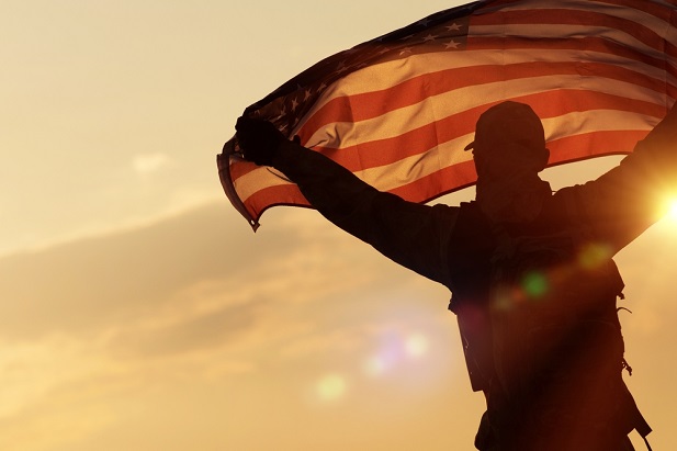silhouette of person holding U.S. flag above head