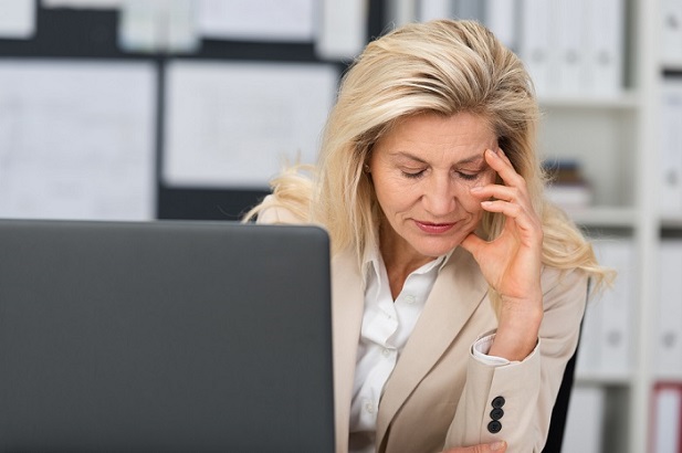 woman at laptop, hand to forehead in worry