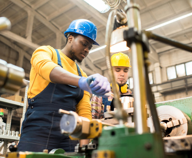 Multi-ethnic,Team,Of,Workers,Wearing,Overalls,And,Protective,Helmets,Using