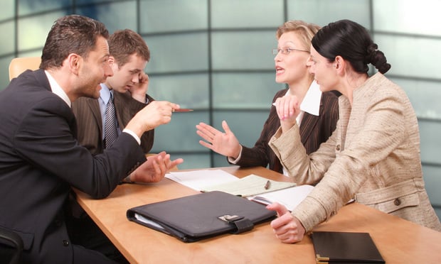 Four business people sitting at a table arguing