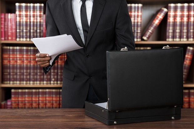 closeup of man with briefcase in front of law books