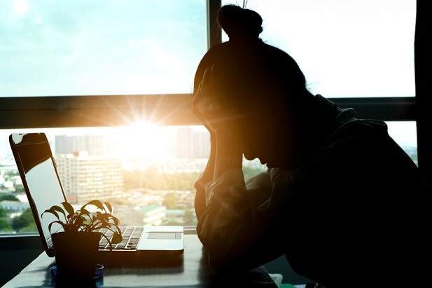 bent over woman silhouetted at office window