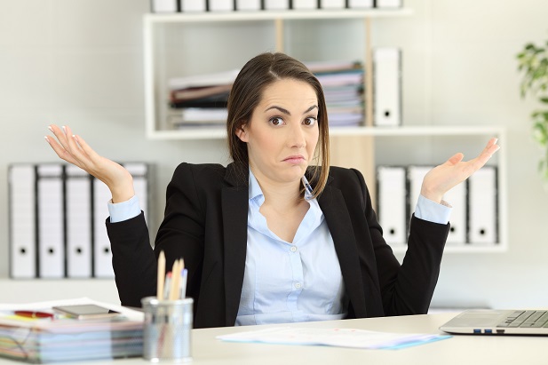 Confused businesswoman shrugging in office.