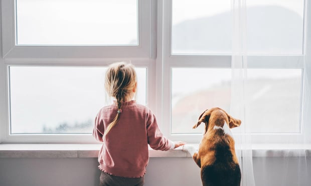 Dog and baby girl staring out a large window.