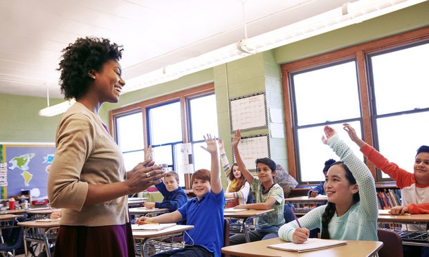 School, teacher and children raise their hands to ask or answer an academic question for learning. Diversity, education and primary school kids speaking to their woman educator in the classroom.