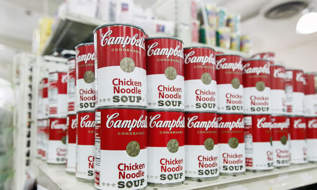 Cans of Campbell's chicken noodle soup stand on a shelf in a supermarket. 