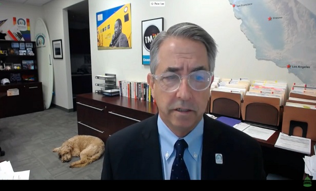 Peter Lee, in an office, with a dog sleeping behind him in the background